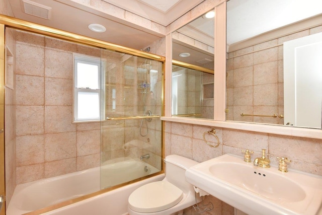 full bath with tasteful backsplash, visible vents, bath / shower combo with glass door, toilet, and a sink