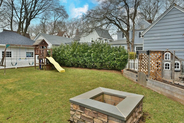 view of yard with an outdoor fire pit, a playground, and fence