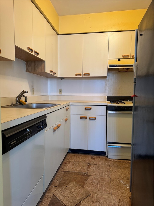 kitchen featuring white cabinets, white appliances, light countertops, and a sink