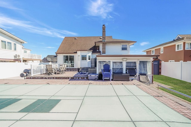 rear view of property with a fenced backyard, a chimney, and a patio