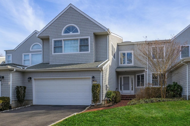 shingle-style home featuring a garage, roof with shingles, aphalt driveway, and a front yard