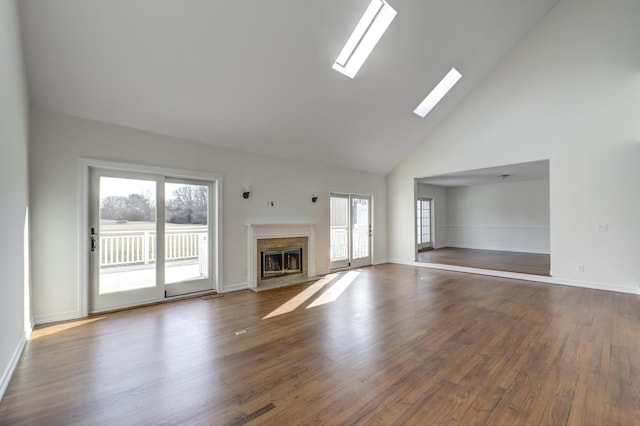 unfurnished living room featuring high vaulted ceiling, dark wood-type flooring, a skylight, a fireplace, and baseboards