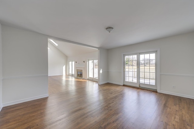 unfurnished living room featuring lofted ceiling, baseboards, wood finished floors, and a glass covered fireplace