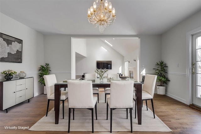 dining space with lofted ceiling, wood finished floors, and a notable chandelier