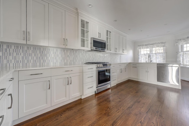 kitchen featuring white cabinets, light countertops, appliances with stainless steel finishes, tasteful backsplash, and glass insert cabinets