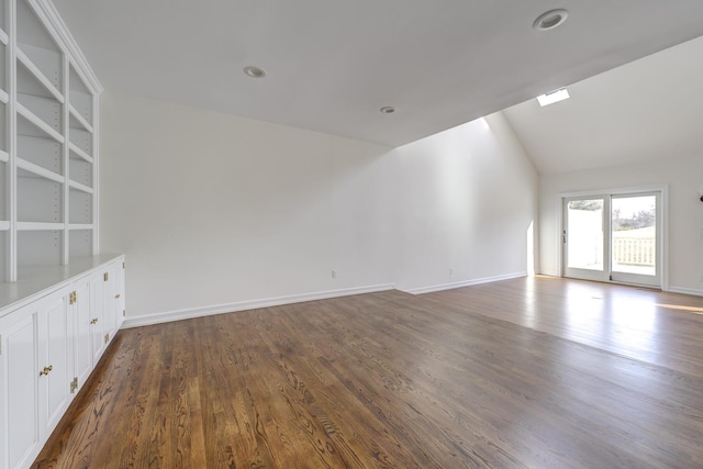 spare room with dark wood-style flooring, vaulted ceiling, and baseboards