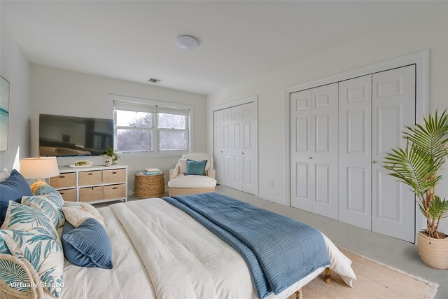 carpeted bedroom featuring two closets, visible vents, and baseboards