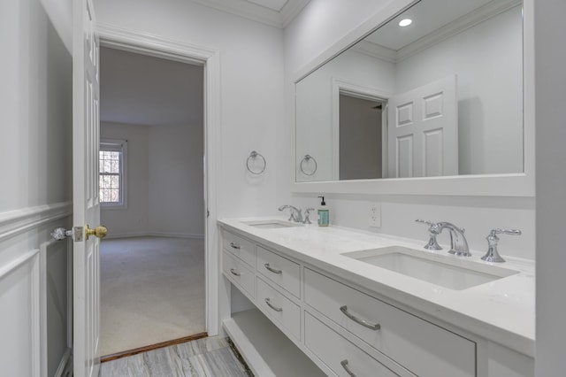 bathroom with crown molding, a sink, baseboards, and double vanity