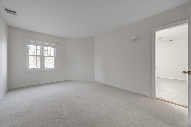 unfurnished room with baseboards, visible vents, and light colored carpet