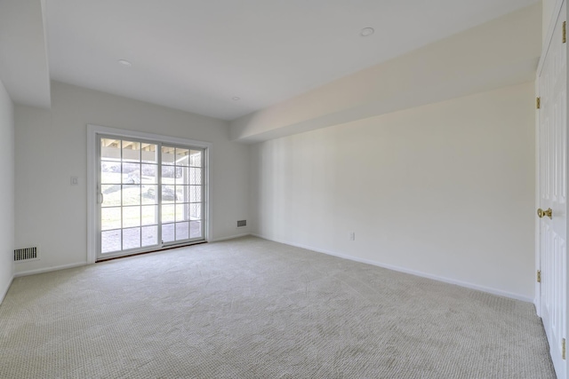 empty room featuring light carpet, visible vents, and baseboards