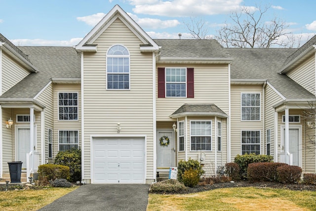 traditional home with roof with shingles, driveway, and an attached garage