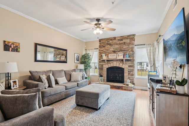 living area featuring ceiling fan, a fireplace, visible vents, light wood-type flooring, and crown molding