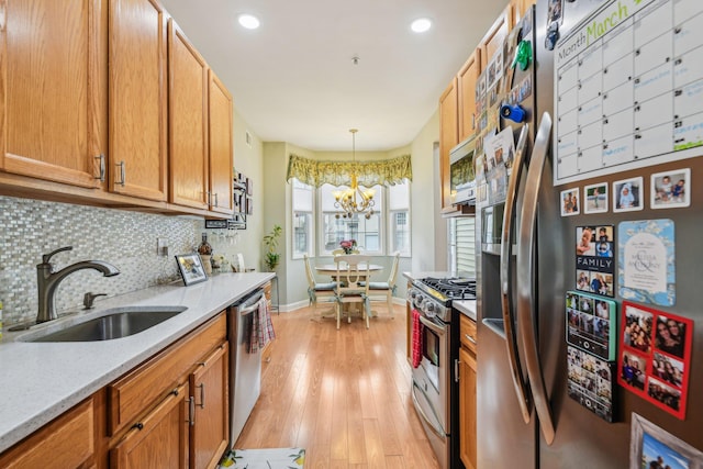 kitchen with tasteful backsplash, baseboards, stainless steel appliances, light wood-type flooring, and a sink