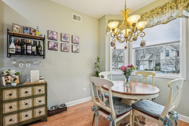 dining room with a chandelier, light wood finished floors, visible vents, and baseboards