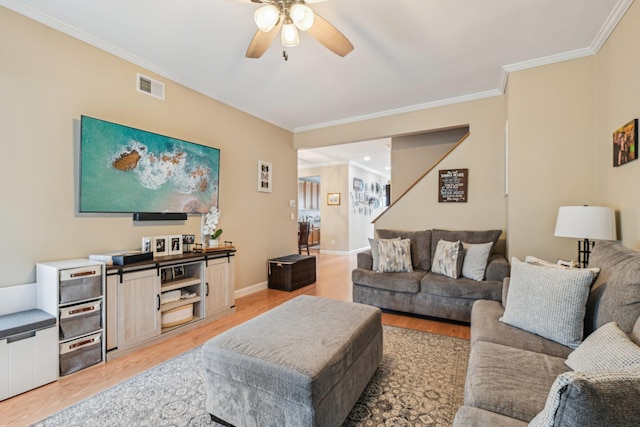 living room with light wood-style floors, visible vents, and ornamental molding