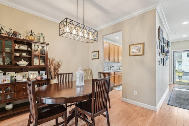 dining space featuring recessed lighting, crown molding, light wood-style flooring, and baseboards