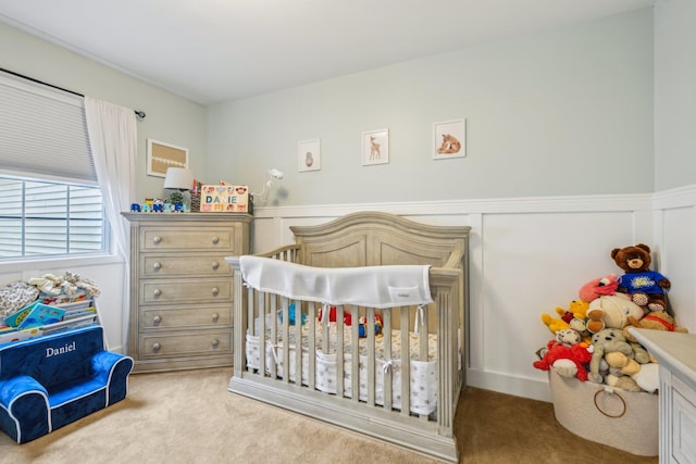 bedroom with light carpet and a nursery area