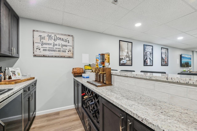 kitchen with light wood finished floors, recessed lighting, a paneled ceiling, light stone countertops, and baseboards