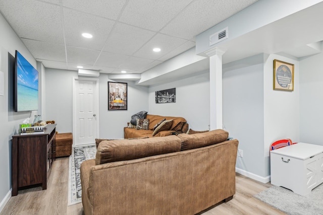 living room with visible vents, light wood-style flooring, baseboards, and a drop ceiling