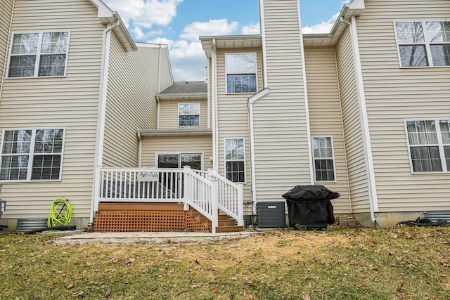 rear view of property featuring a chimney, a deck, and a yard