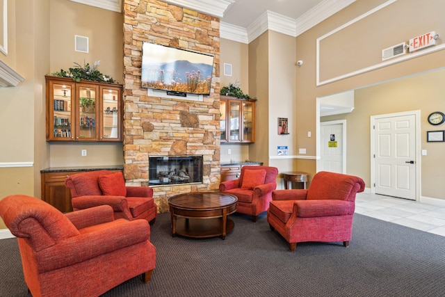 living area with light tile patterned flooring, a fireplace, a towering ceiling, visible vents, and crown molding