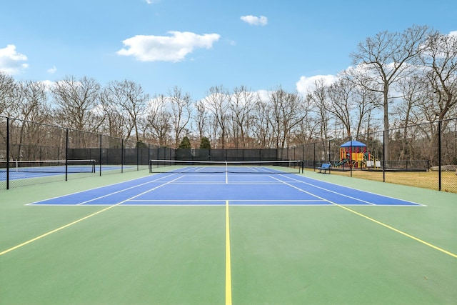 view of tennis court featuring community basketball court, fence, and playground community