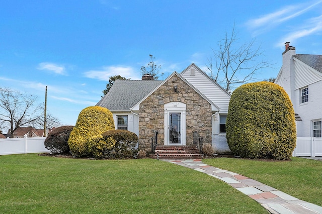 view of front facade featuring a chimney, fence, and a front yard