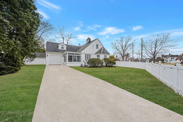 view of front of home with concrete driveway, a front lawn, and a fenced backyard