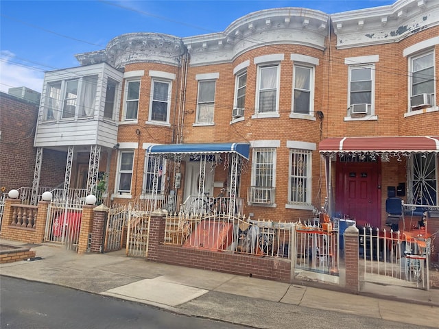 townhome / multi-family property featuring cooling unit, brick siding, and fence