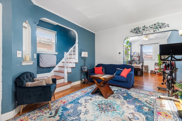 living room with baseboards, stairs, arched walkways, and wood finished floors