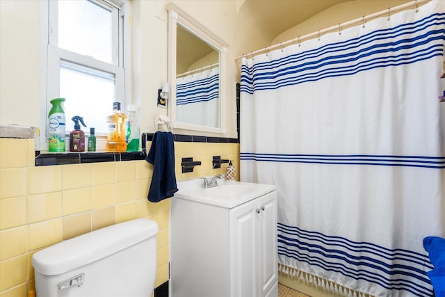 bathroom with toilet, tile walls, and vanity