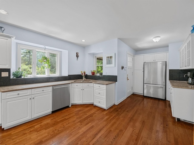 1 Finnegan Ln, Montebello, NY 10901 - kitchen featuring stainless steel appliances, tasteful backsplash, white cabinetry, light wood-style flooring, and glass insert cabinets