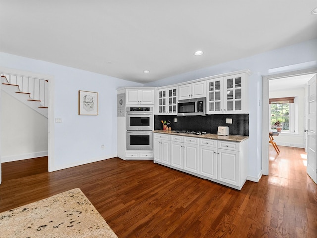 1 Finnegan Ln, Montebello, NY 10901 - kitchen featuring stainless steel appliances, dark wood-type flooring, white cabinetry, glass insert cabinets, and backsplash