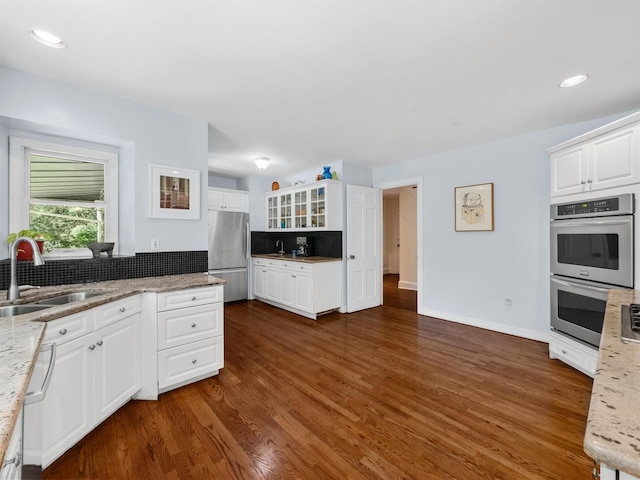 1 Finnegan Ln, Montebello, NY 10901 - kitchen featuring appliances with stainless steel finishes, backsplash, dark wood-type flooring, glass insert cabinets, and white cabinets