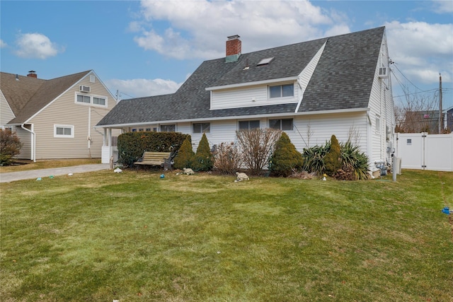 exterior space featuring a front lawn, a chimney, a shingled roof, and fence