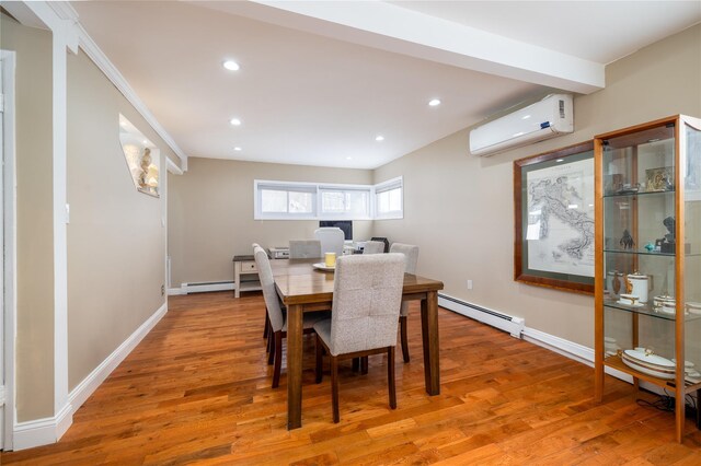 dining room featuring a baseboard heating unit, a wall unit AC, light wood-style flooring, and baseboards