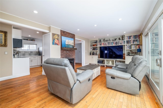 living area featuring a brick fireplace, light wood-style flooring, and recessed lighting