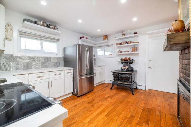 kitchen with tasteful backsplash, white cabinets, light countertops, and freestanding refrigerator