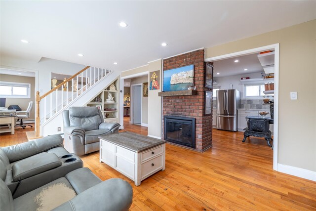 living area with stairway, light wood-type flooring, a fireplace, and recessed lighting