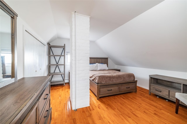 bedroom with light wood finished floors and vaulted ceiling