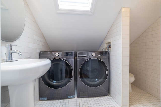 clothes washing area featuring laundry area, separate washer and dryer, tile walls, and tile patterned floors