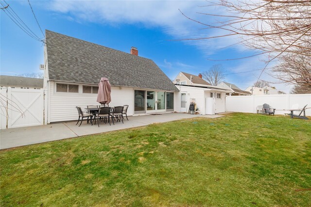 back of property featuring a chimney, fence, a lawn, and a patio