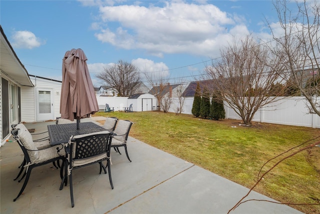 view of patio with outdoor dining space, a shed, an outdoor structure, and a fenced backyard