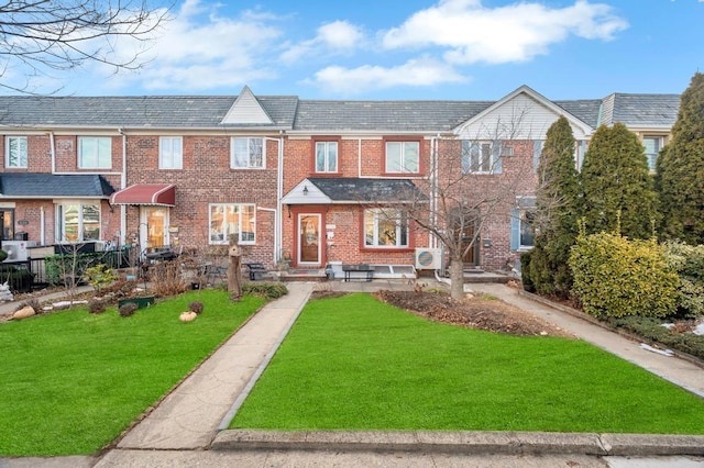 multi unit property featuring a front yard, brick siding, and a high end roof