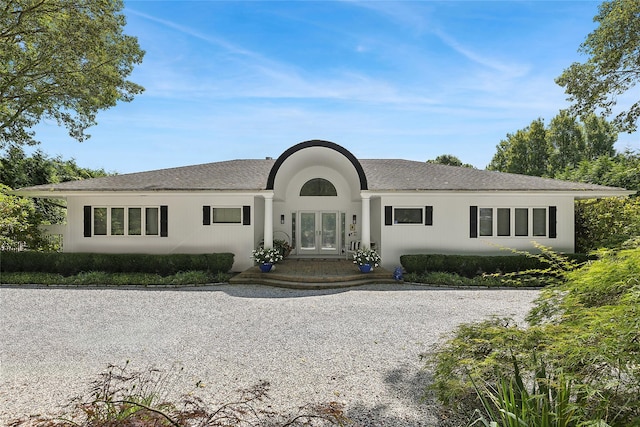 ranch-style home with french doors, gravel driveway, and stucco siding