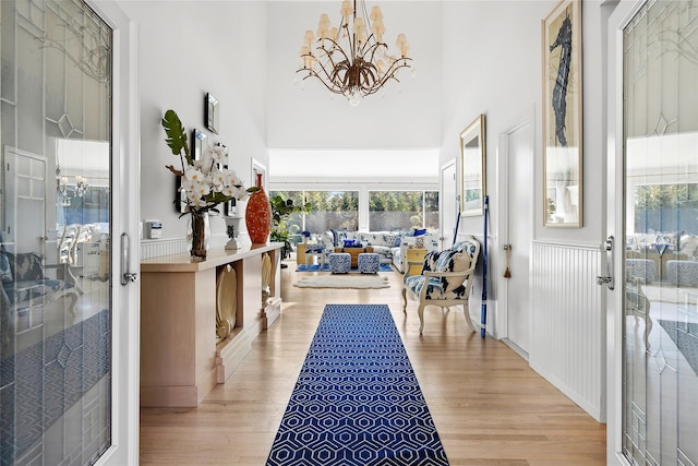 foyer with a chandelier, wainscoting, wood finished floors, and a towering ceiling