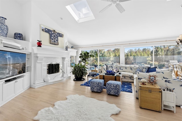 living area with a skylight, a premium fireplace, ceiling fan, wood finished floors, and high vaulted ceiling