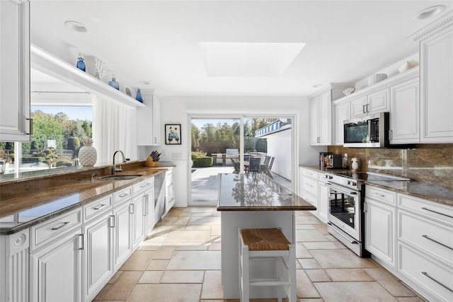 kitchen featuring stainless steel appliances, a sink, backsplash, and stone tile floors