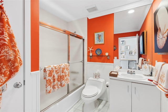 full bath featuring tile patterned flooring, toilet, a wainscoted wall, vanity, and combined bath / shower with glass door