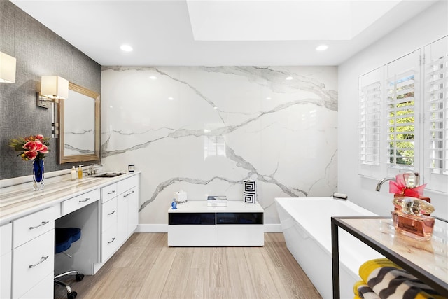 full bath with recessed lighting, a freestanding bath, vanity, and wood finished floors